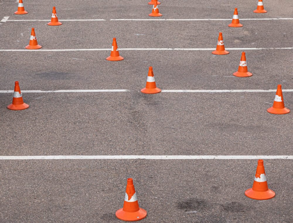 Man in helmet on motor-cycle making exercises on car-park among orange traffic cones Man in helmet on motor-cycle making exercises on car-park among traffic cones
